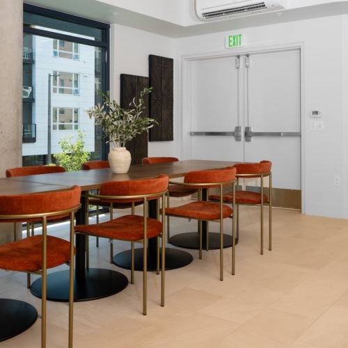 large table and seating in a room with windows pillar and art on the wall